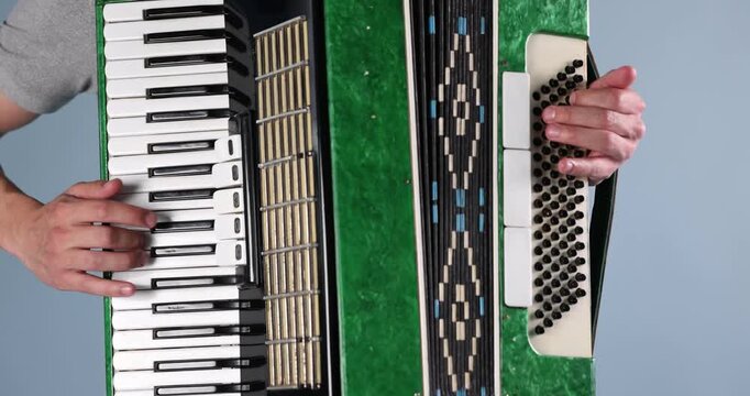 Man playing piano accordion on light background, closeup
