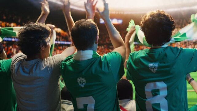 Football fans in green shirts clapping and cheering from stadium stands for fan culture, stadium atmosphere and team support content.