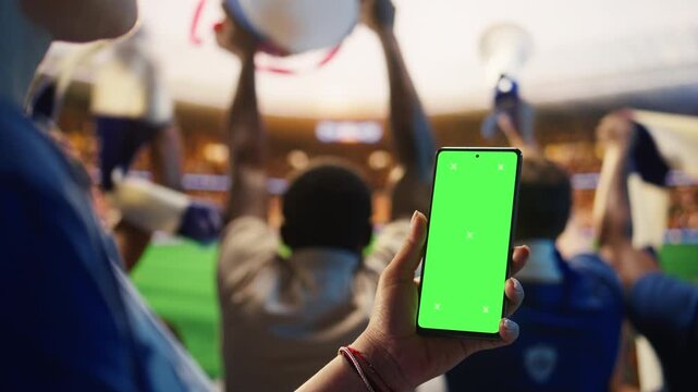 Close up of isolated screen smartphone used by football supporter in stadium to follow live scores for sports betting, editable screen and fan reaction content.