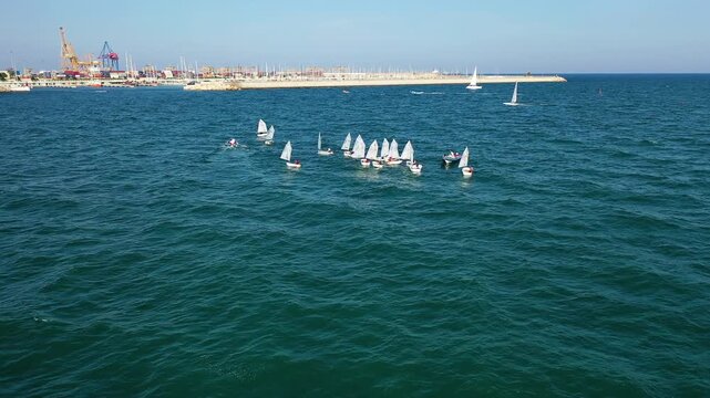 Aerial view of groupes of Optimist Class sailboats before the starting of a regatta in Alicante, in the Mediterranean coast of Spain.