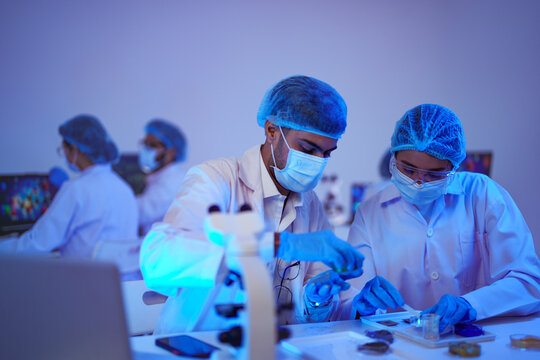 Science colleagues precisely analyse specimens using microscope and samples in a high-technology biolab as part of advanced scientific research using modern laboratory equipment.