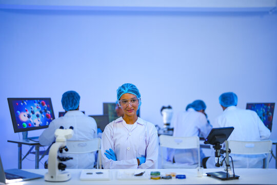 A biotech scientist precisely works confidently at a laboratory microscope in a dramatic modern biolab as part of advanced scientific research using modern laboratory equipment.