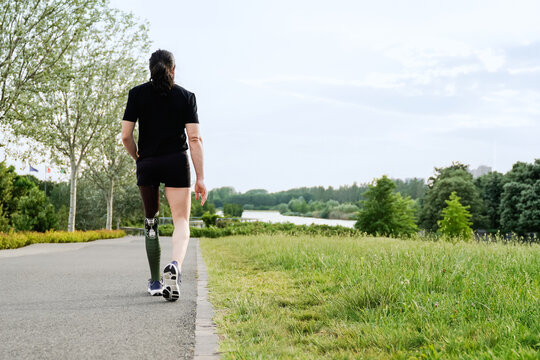 Athletic man with disability doing sports at park city - Man with prosthetic leg walking outdoors - Disability, healthy lifestyle concept