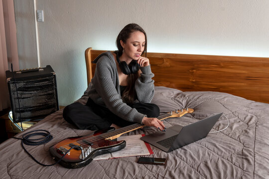Independent Female Bass Player Creating Music at Home with Laptop