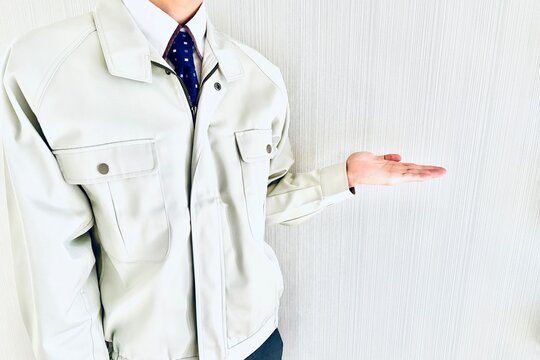 提案のポーズをする作業着姿の男性