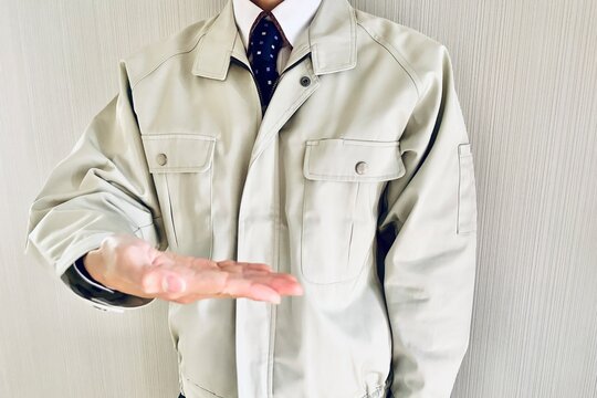 提案のポーズをする作業着姿の男性