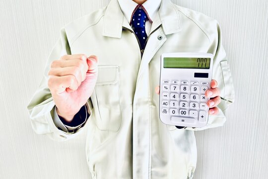 電卓を持ってガッツポーズする作業着の男性
