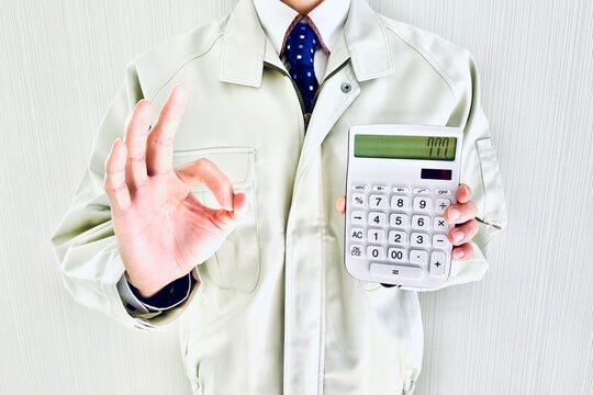 電卓を持って丸サインをする作業着姿の男性