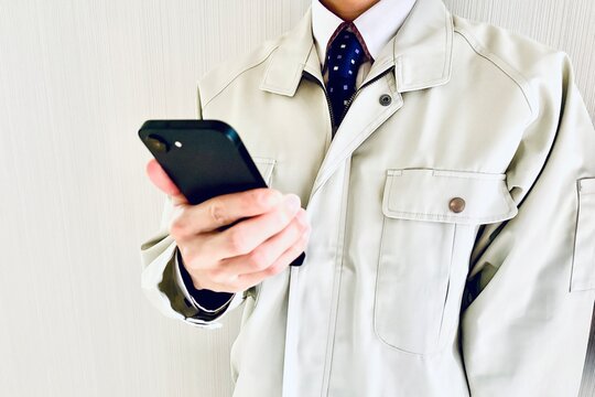スマホを持つ作業着姿の男性ビジネスマン