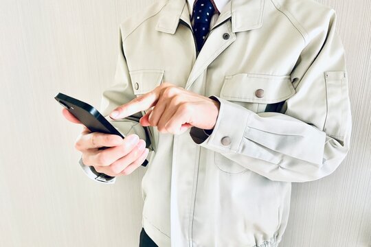スマホを持つ作業着姿の男性ビジネスマン