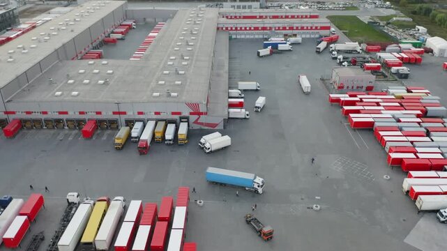 Aerial All-Round View of Large Logistics Hub with Trucks and Trailers at Loading Docks | Orbiting Drone Shot of Distribution Warehouse Complex | Freight Transport Facility