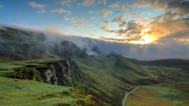 Beautiful Sunrise over Green Mountain Cliffs with Fog and Mist Rolling down the Valley