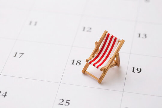 Red beach chair on white blank calendar background copy space. Annual leave travel period for relaxation concept. Period of paid time off (PTO) granted to employees by their employer.