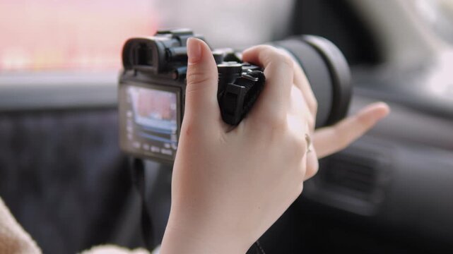 Person holds camera inside car. Hands steady, focused on capturing view. Soft light, calm mood. Ideal for travel, vlogging, or documentary use