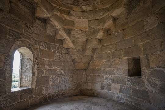 Interior of a round stone tower, corner where masonry walls curve inward to support the ceiling.