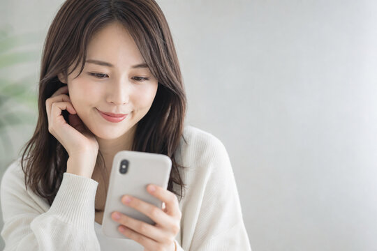 スマホを見る笑顔の日本人女性 Generative AI