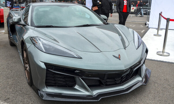 Grey Chevrolet Corvette C8 Z06, high performance American sports car in metallic gray with aggressive front splitter, sharp LED headlights, and custom bronze wheels