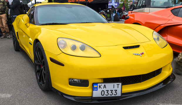 Bright yellow Chevrolet Corvette C6 Z06 at an outdoor car show in Kyiv. American sports car with black wheels, tinted headlights, and carbon front splitter