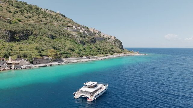 Yachting in the crystalline turquoise waters of Limeni village on Mani Peninsula with mountains and stone built hotels in the backdrop in summer daylight, Drone shot