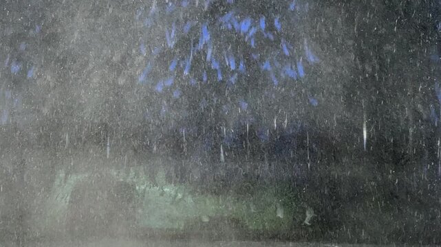 A view through the front window of a car going through an automatic car wash machine with Spinning brushes, water and soap suds.