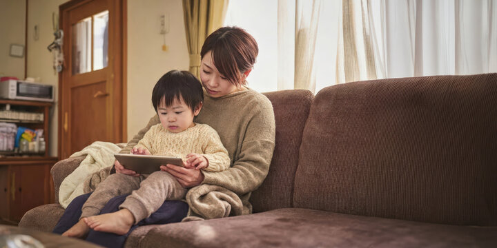 ソファでタブレットを見る母と子