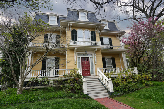 Large old yellow clapboard house with mansard roof