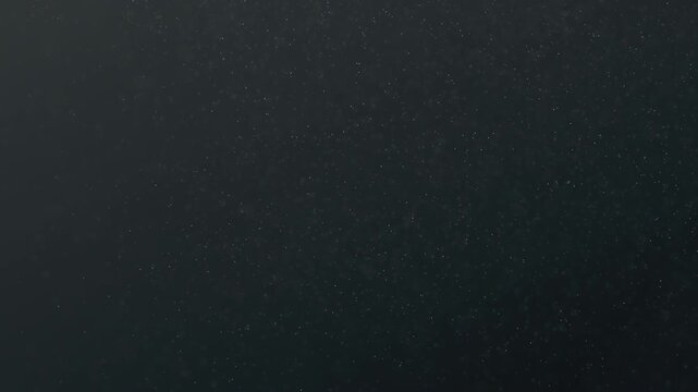 Fine dust particles floating and swirling in the air against a dark, slightly gradient background. Looping animation in 4K resolution.