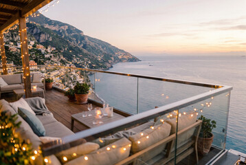 Fototapeta premium Outdoor balcony lounge with fairy lights overlooking a steep coastal mountain town at twilight