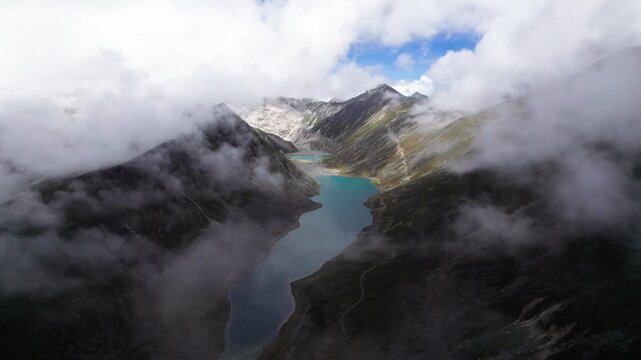 Drone view of Zhegong three lakes in Mount Kula Kangri in rainy sunny cloudy day, well-built hiking trail circling its shore. 4k real time footage travel concept b roll shot.