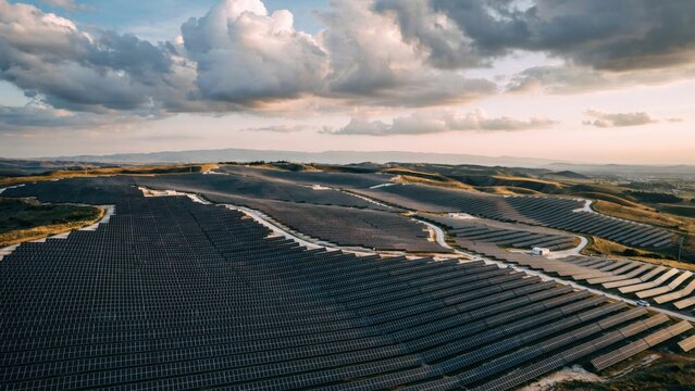 Aerial view of large solar farm on rolling hills at sunset