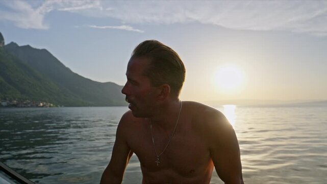 Golden hour shot of a man on a boat on Lake Geneva, with calm water, mountains, and warm sunset light creating a premium summer lifestyle mood.