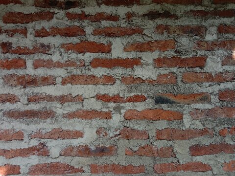 Close-up of a weathered red brick wall with messy cement mortar texture, 