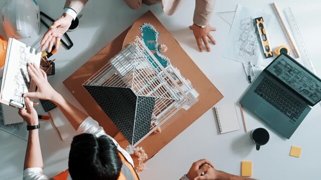 Close up of civil engineer hand holding blueprint while working together to plan building construction by using house model and shaking hand or making a deal or contract with manager. Alimentation.