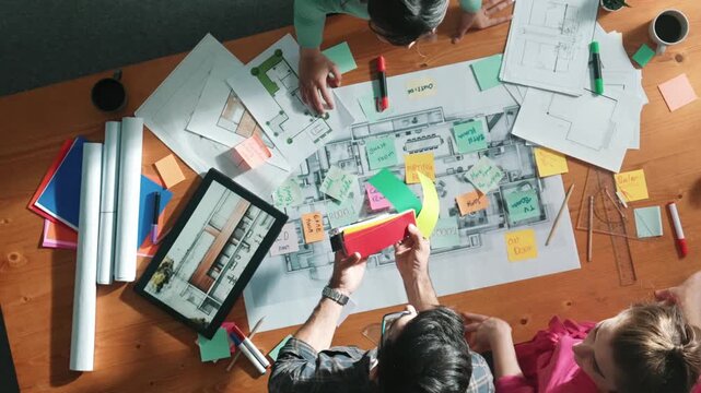 Top view of engineer working together to design building construction while standing at meeting table with blueprint and notes. Top view of interior designer choosing color from palettes. Symposium.