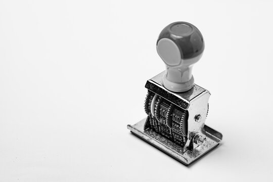 Close-up of a vintage manual date stamper in black and white on white background