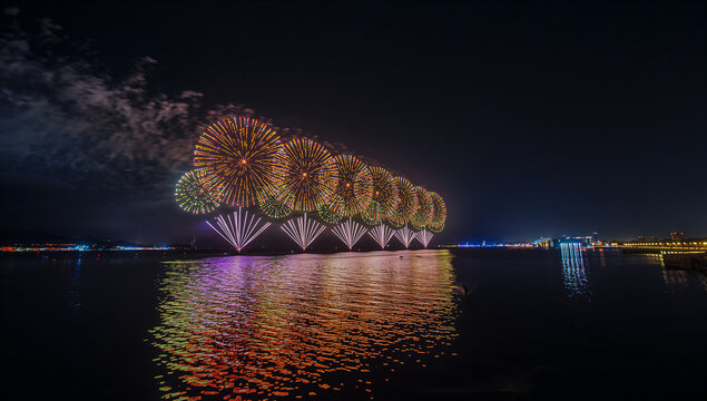 海上でドローンの光と花火が共演する未来的な夜景