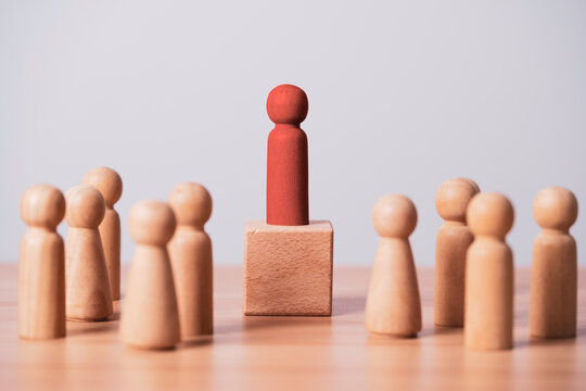Red wooden leader standing above a crowd symbolizes leadership, authority, confidence, influence team management, career success, business strategy motivation and organizational growth.