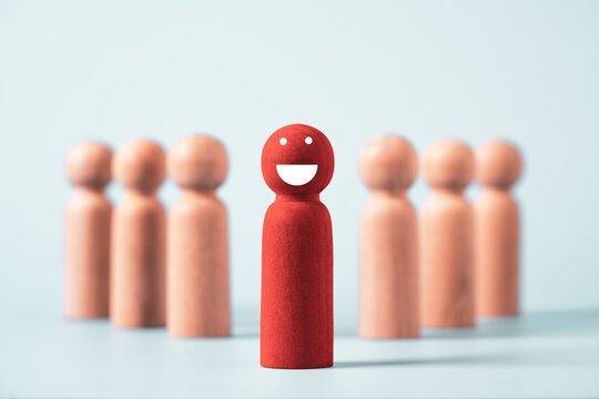 Smiling red wooden figure standing confidently among a crowd symbolizes positive mindset, confidence, optimism, resilience, emotional wellbeing, personal growth, leadership and self motivation.