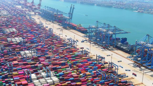 Aerial drone view of Qingdao fully automated smart container port, unmanned intelligent dock with automated cranes and container stacks for global shipping logistics。