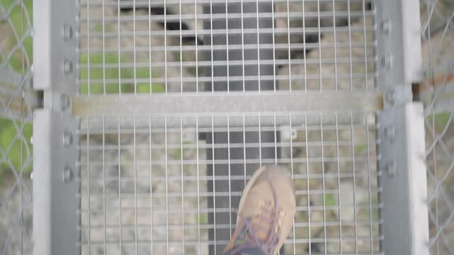 Point of view shot of a person's feet walking carefully across a metal suspension bridge in zermatt