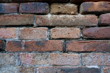 Fototapeta premium Weathered red brick wall with natural white efflorescence and aged texture, creating a rustic background for architectural and design projects.