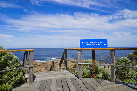 Cape Leeuwin wooden boardwalk lookout with southern ocean and indian ocean sign over coastal horizon