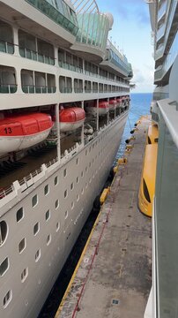 View from balcony looking at two cruise ships at dock next to each other at Bahamas port. Daytime vertical shot. Travel and tourism content.