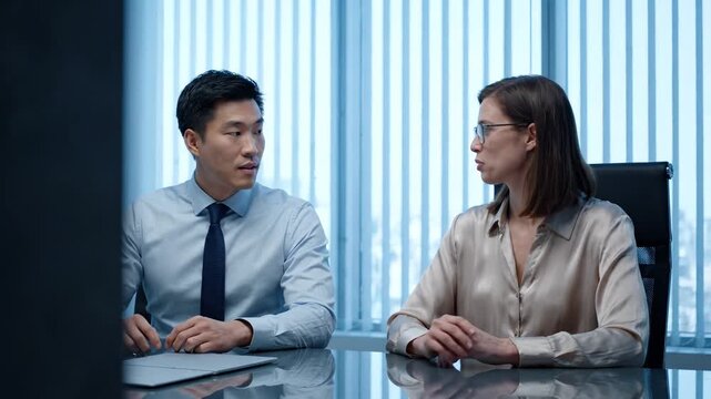 Two professionals discussing business strategy in modern office meeting