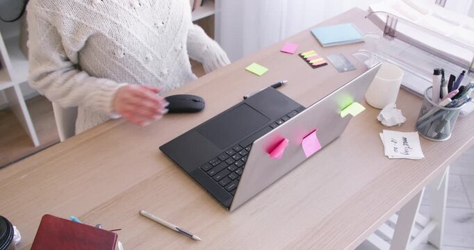 Female worker. Office routine. Unrecognizable entrepreneur writing in notebook at desk with laptop sticky notes for professional occupation.