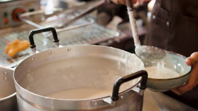 Chef Ladling Hot Asian Congee Rice Porridge Into Serving Bowl