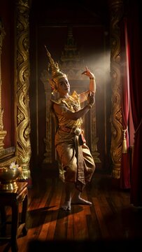 Traditional Thai dancer performing in ornate temple setting with sunlight