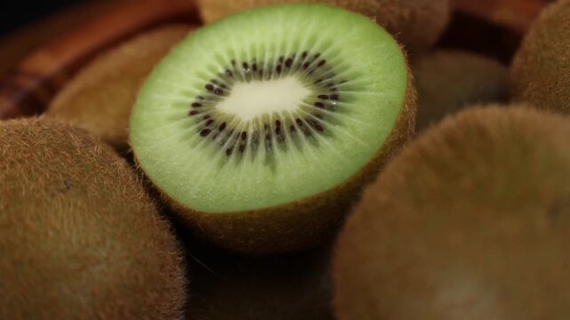 Close-up of fresh kiwi fruits arranged on a wooden table. Whole and sliced kiwis showing their vibrant green flesh and tiny black seeds under natural light. Ideal for themes of healthy eating, fresh f