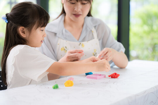 母親や先生と一緒に粘土遊びを楽しみながら創造力を育む親子・知育遊びの時間　発達支援や療育、子育てのイメージ