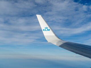 Fototapeta premium Winglet of a KLM Royal Dutch Airlines airplane flying high in the blue sky, view from the window